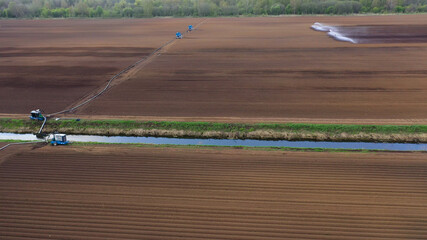 aerial view crop irrigation machine using center pivot sprinkler system. An irrigation pivot watering agricultural land. Irrigation system watering farm land.