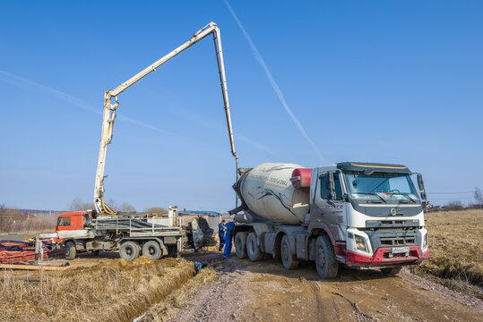 LENINGRAD REGION, RUSSIA - MARCH 28, 2021: A concrete mixer truck and a concrete pump on the construction of a country house on a sunny March day