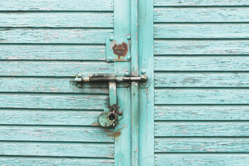 Blue paint wooden garage door. Metal padlock background. Peeling paint wood. Vintage rustic gate. Empty copy space grunge door texture.