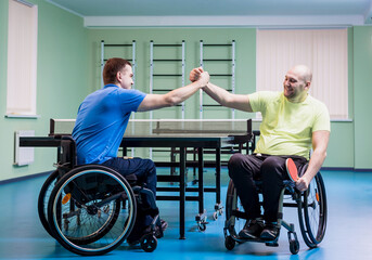 Disabled adult men shaking hands after playing table tennis