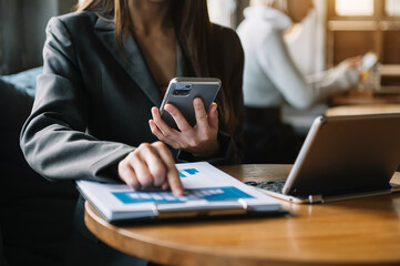 Confident businesswoman working on laptop and tablet