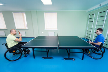 Adult disabled men in a wheelchair playing table tennis