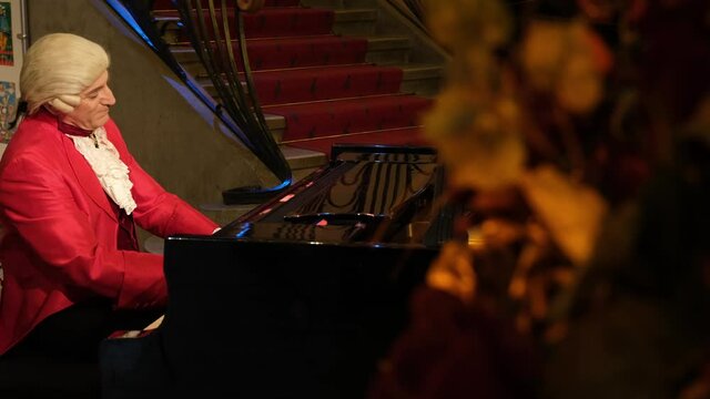 A man pianist, wearing clothes of the 18th century nobility, playing a rondo by Wolfgang Amadeus Mozart on a piano.