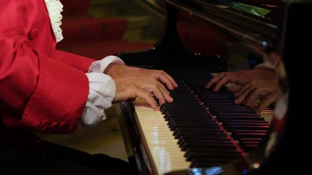 A man pianist, wearing clothes of the 18th century nobility, playing a rondo by Wolfgang Amadeus Mozart on a piano.