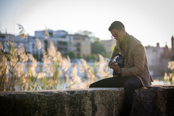 Latin man playing guitar in the street during sunset against light