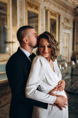 Portrait of the groom and the pregnant bride. Newlyweds in the ceremony hall.