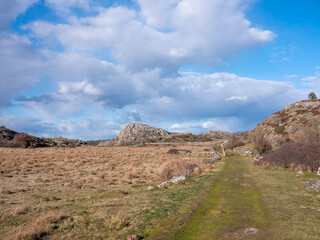 Countryside landscape with road, meadows and stone fences and granite hills in the background. Shot in Sweden, Scandinavia at Säby Kile natural reserve