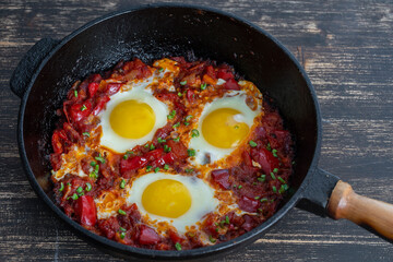 Shakshuka, fried eggs with tomatoes, onion, red pepper and spices in cast iron pan