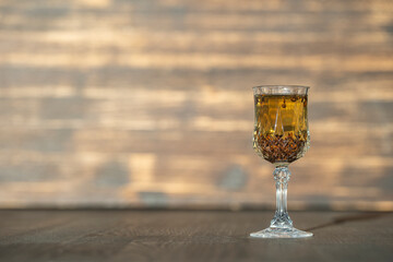 Homemade birch buds tincture in a wine crystal glass on a wooden table background