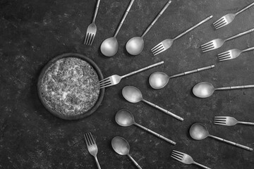 Ceramic bowl with vegetable frittata and forks and spoons look like sperm competition. Spermatozoons floating to ovule - obrazy, fototapety, plakaty
