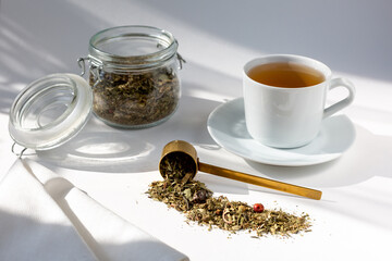 natural tea in a jar and a cup of tea, tea scattered on the table