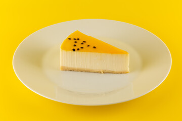 a piece of passion fruit cheesecake on a white plate on a yellow background
