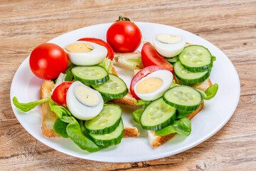 Fried white bread toasts with vegetable and egg slices on a plate