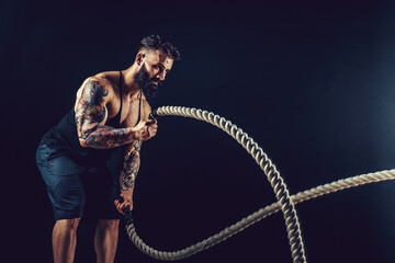 Muscular man working out with heavy rope. Photo of man with naked torso. Strength and motivation. 