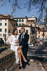 Newlyweds are walking in the old town. The bride and groom are resting on the bench.