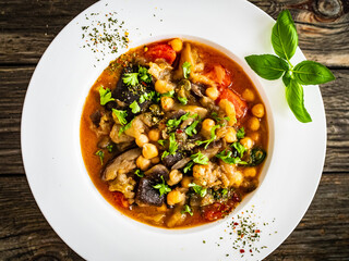 Delicious stew - aubergine with tomatoes and chickpeas on wooden table
