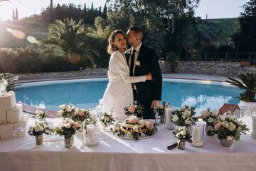 The bride and groom at the wedding table are receiving congratulations. Newlyweds by the pool.