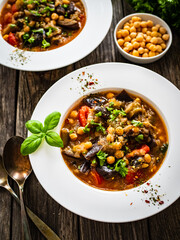 Delicious stew - aubergine with tomatoes and chickpeas on wooden table
