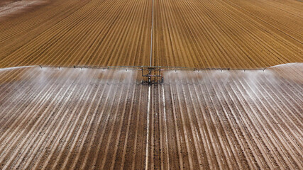 aerial view crop irrigation machine using center pivot sprinkler system. An irrigation pivot watering agricultural land. Irrigation system watering farm land.