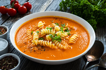 Tomato soup with noodles on wooden table
