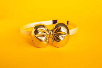 Decorative hair hoop for girls with a gold bow on a yellow background