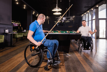 Fototapeta na wymiar Adult men with disabilities in a wheelchair play billiards in the club