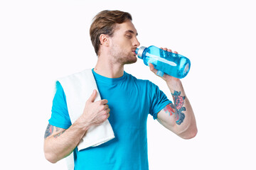 man athlete drinks water from a bottle on a white background and a towel on his shoulder