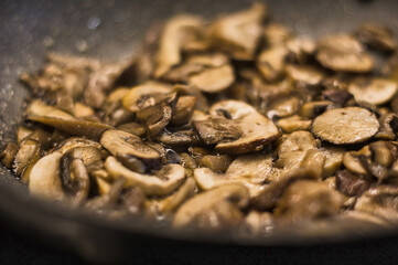 Desenfoque selectivo de setas y champiñones cocinándose en una sartén con aceite de oliva.