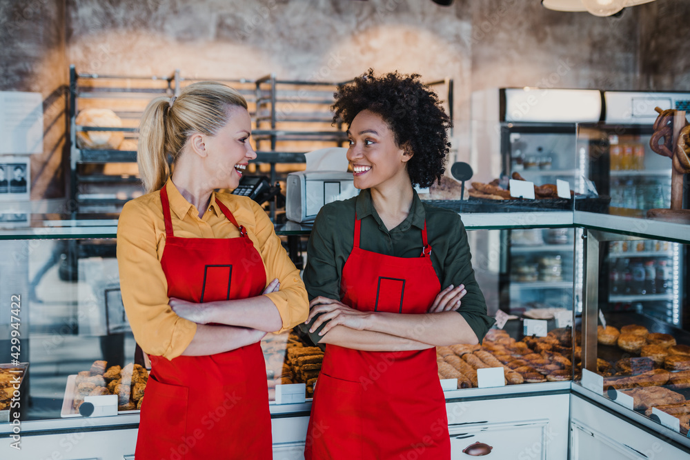 Wall mural beautiful african american and caucasian female workers working in bakery.