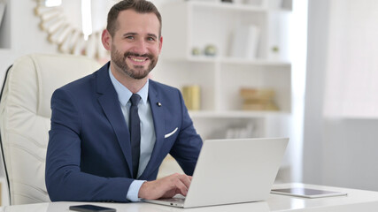 Cheerful Businessman with Laptop Smiling at the Camera 