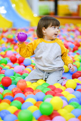 Fototapeta na wymiar Creative development of children. The kid plays with colored balls in the children's development center.