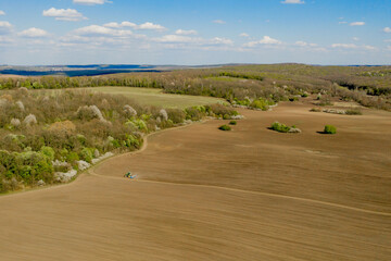 Aerial view large tractor cultivating a dry field. Top down aerial view tractor cultivating ground...