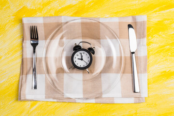 Alarm clock on the plate with fork and knife, lunch time concept, top view with copy space
