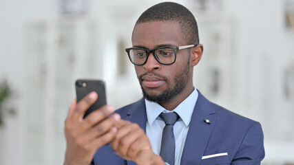 Obraz na płótnie Canvas Portrait of Serious African Businessman using Smartphone 