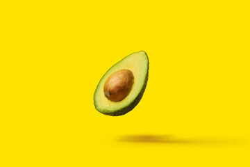 avocado with a bone fly in the air on a yellow background. Top view, flat lay