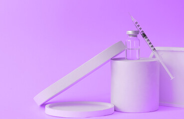 Syringe and ampoule on podium on violet color background. Vaccination concept.