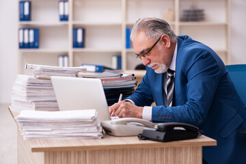 Obraz premium Old male employee and too much work in the office
