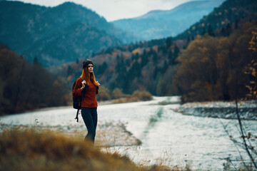 woman on vacation with a backpack on the river bank in the mountains