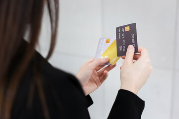Woman in black formal suit holds credit cards in her hands. She was choosing credit cards to use its in financial concept.