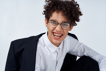 portrait of a curly-haired guy in a shirt in a jacket and glasses 