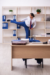 Young male employee doing sport exercises during break