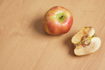 whole good and cut in half rotten apple on wooden background