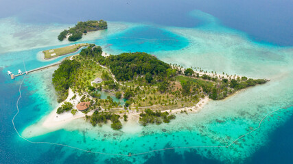 Fototapeta na wymiar Aerial view of Tropical island with sand beach, palm trees by atoll with coral reef. Malipano island, Philippines, Samal.