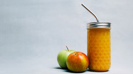Apple juice in glass with metal straw on grey background. Fresh squeezed apple juice with pulp or fruit smoothie. Copy space. Dietary beverage, healthy drink and dieting concept.