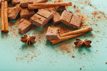 Chocolate with spices and cocoa on a green background.