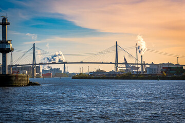 Fototapeta premium sight over port of hamburg industrial area with hamburgs most famous suspension bridge called Kohlbrand bridge, crossing the elbe river during dusk