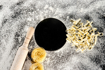 Freshly cooked pasta is lying on a dark surface dusted with flour. Italian pasta. Tagliatelle. Raw pasta. Italian pasta recipe. Top view, copy space