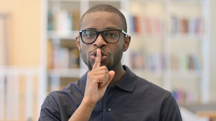 Portrait of Young African Man Putting Finger on Lips