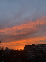 Rooftop view of sunset in Kyiv, Ukraine. Orange, yellow, pink and red sunset. Lifestyle and city tranquility concept. High quality vertical photo