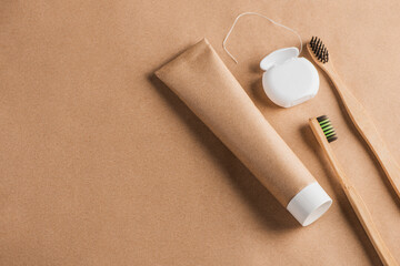 Eco-friendly toothpaste, dental floss and bamboo toothbrushes on craft paper